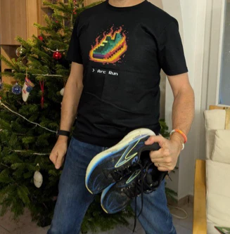A runner wearing the black Arc Run t-shirt, holding running shoes
